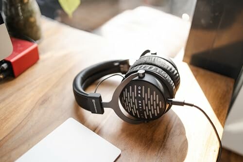 Over-ear studio headphones resting on a wooden desk